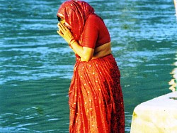 An Indian woman in sari, immersed in the waters of the Ganga River, performs a devotional ritual. Rishikesh, India.